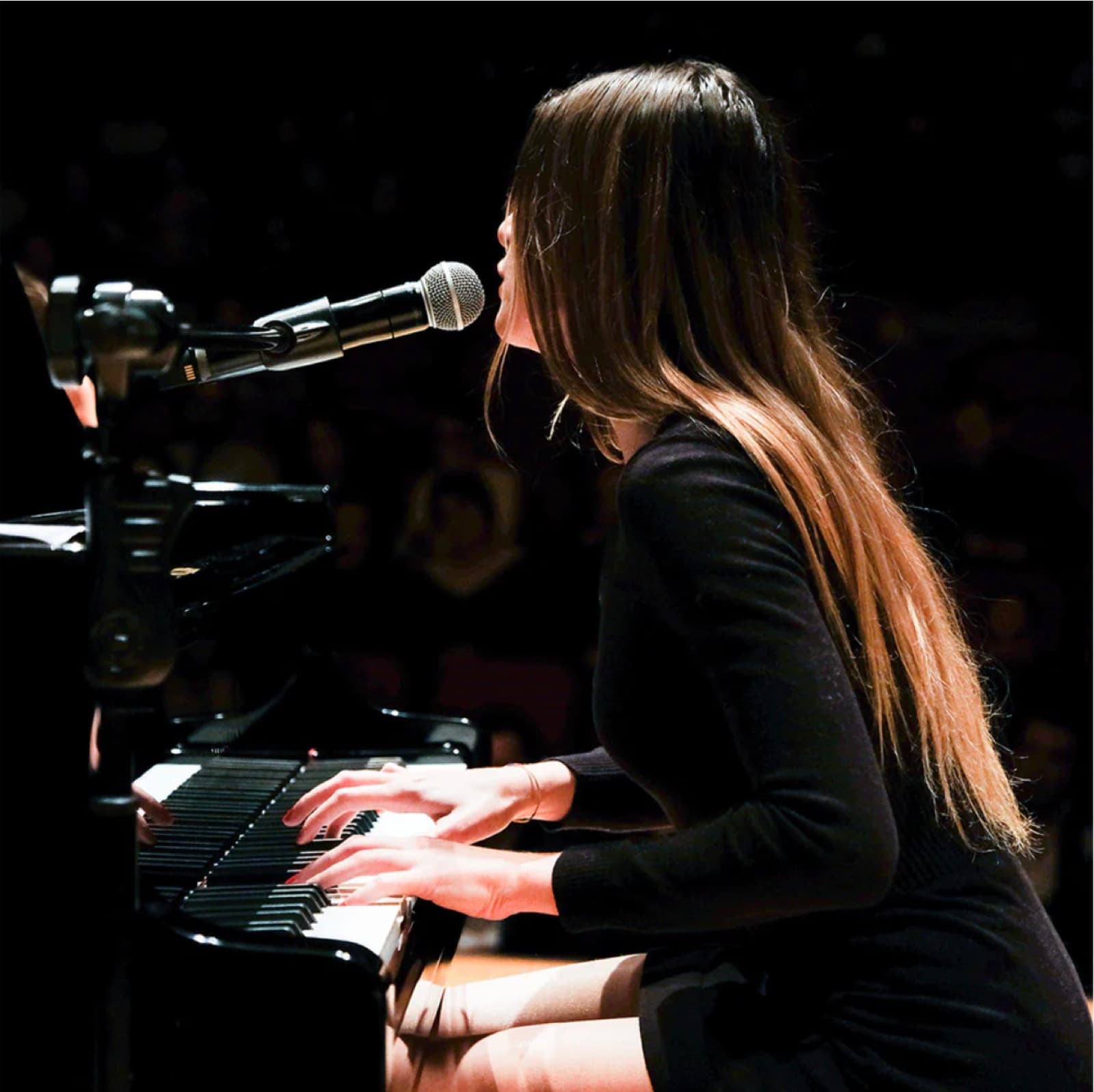 Ceren Soyer at the piano with microphone during a concert performance