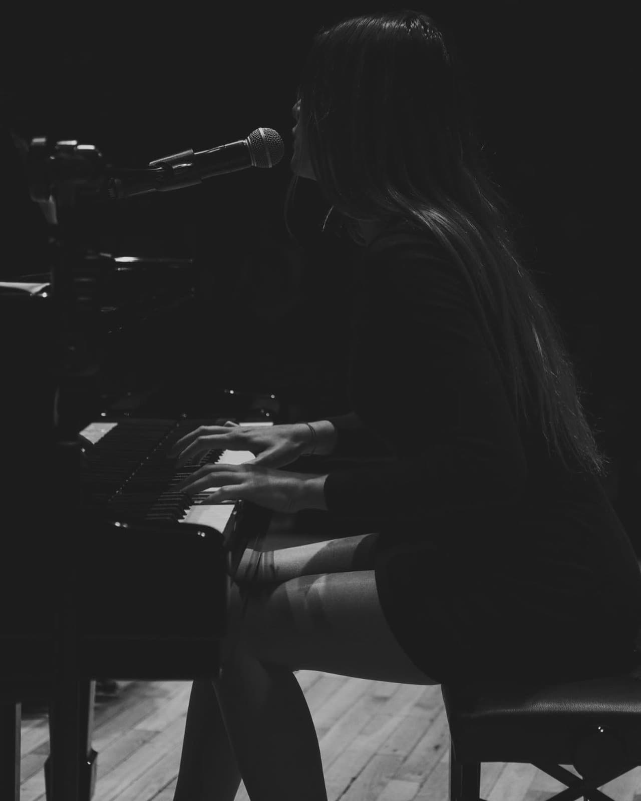 Ceren Soyer singing and playing piano in concert — black and white