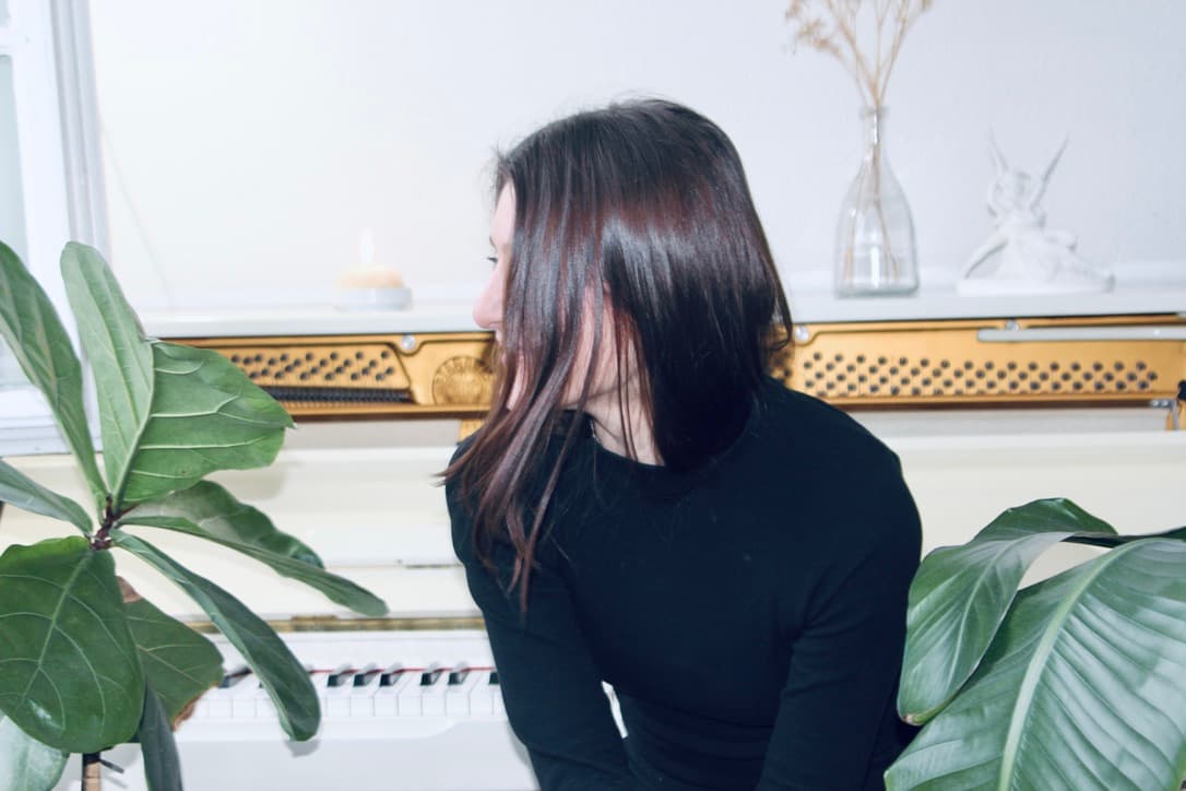 Ceren Soyer at the white upright piano in her Hamburg studio — side profile portrait
